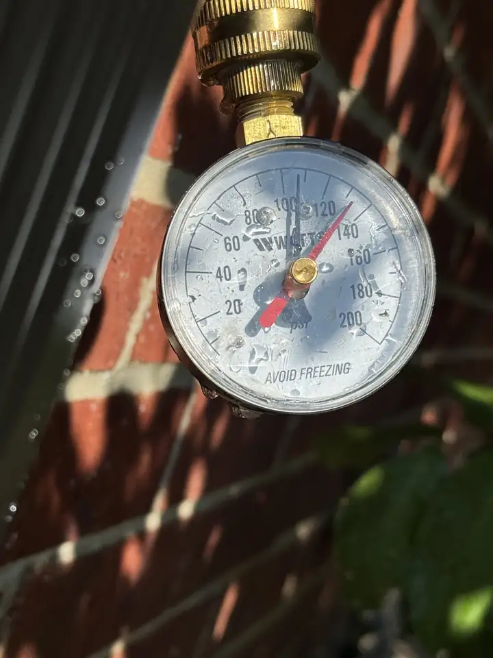 Water pressure gauge reading about 108 PSI at a brick wall, McKinney