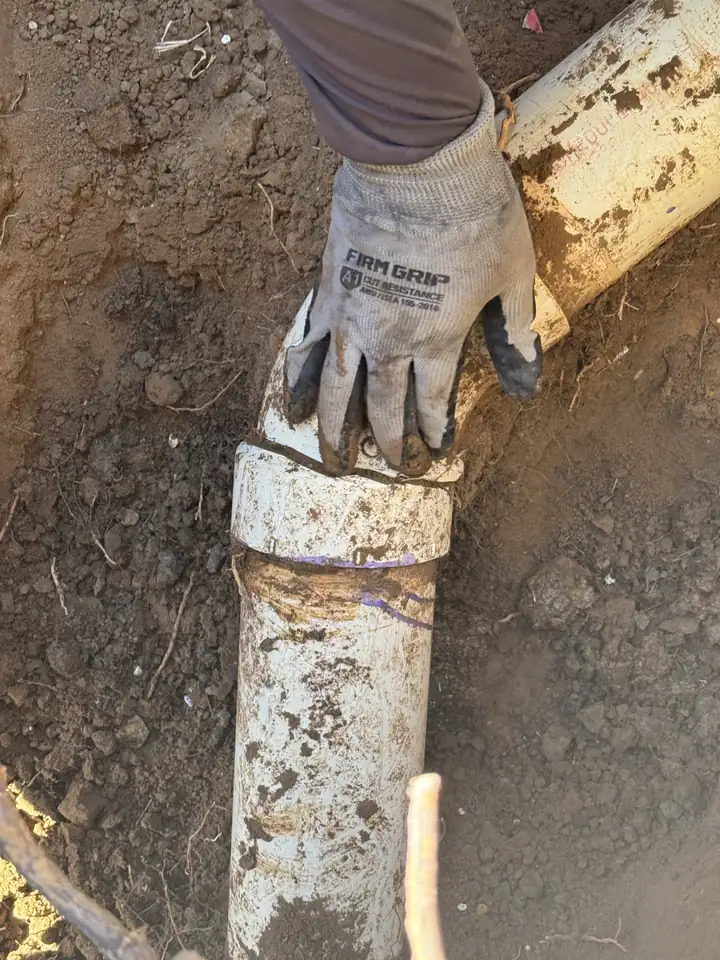 Broken main drain line exposed in a dug hole, sewer line repair