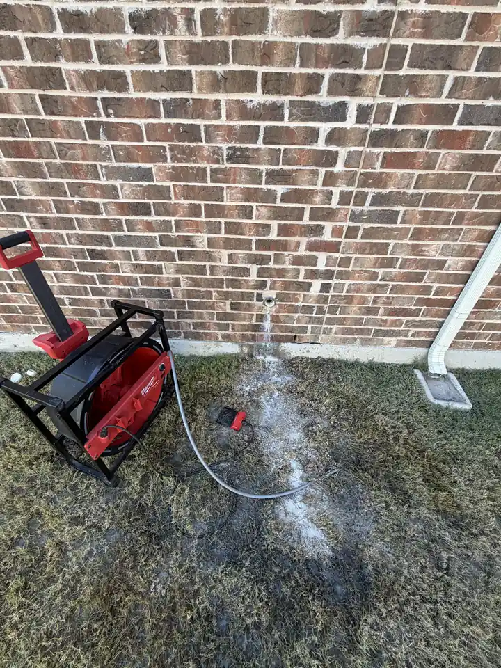 Milwaukee chain snake clearing a kitchen drain line through a wall cleanout, Prosper