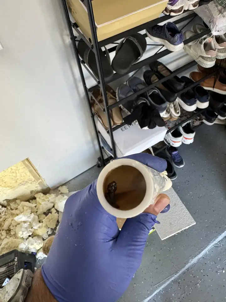 Gloved hand holding a cut out piece of water pipe with a nail hole in it, Frisco