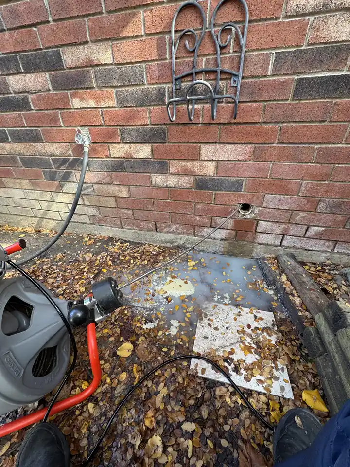 Drum cable machine feeding its cable into a kitchen drain line through a wall cleanout, Plano