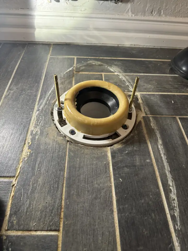 New toilet flange with bolts and a wax ring on a tile floor, Plano