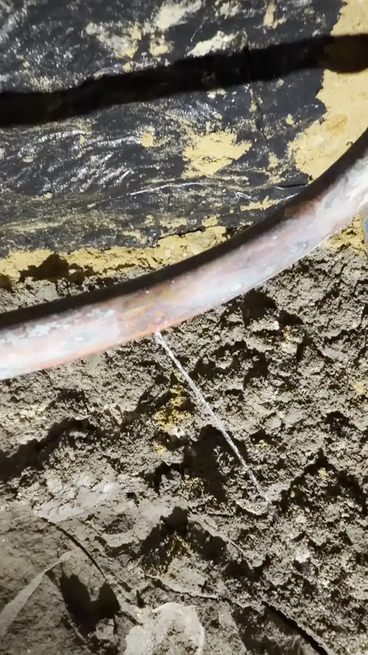 Water spraying from a pinhole in a copper water line under a house slab, slab leak