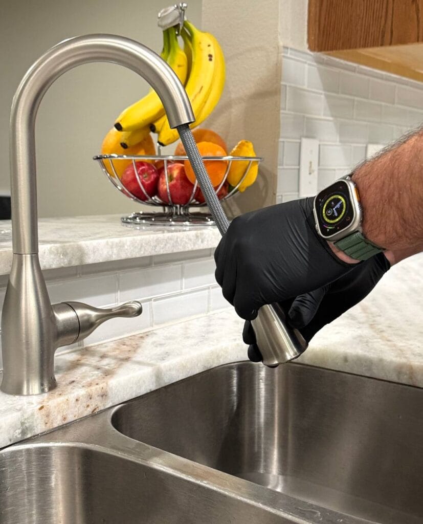 Licensed plumber installing a new kitchen faucet in Frisco home