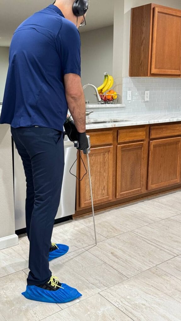 Plumber using advanced leak detection equipment to find hidden water leak inside home in Frisco