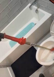Plumber clearing a clogged toilet with a toilet auger