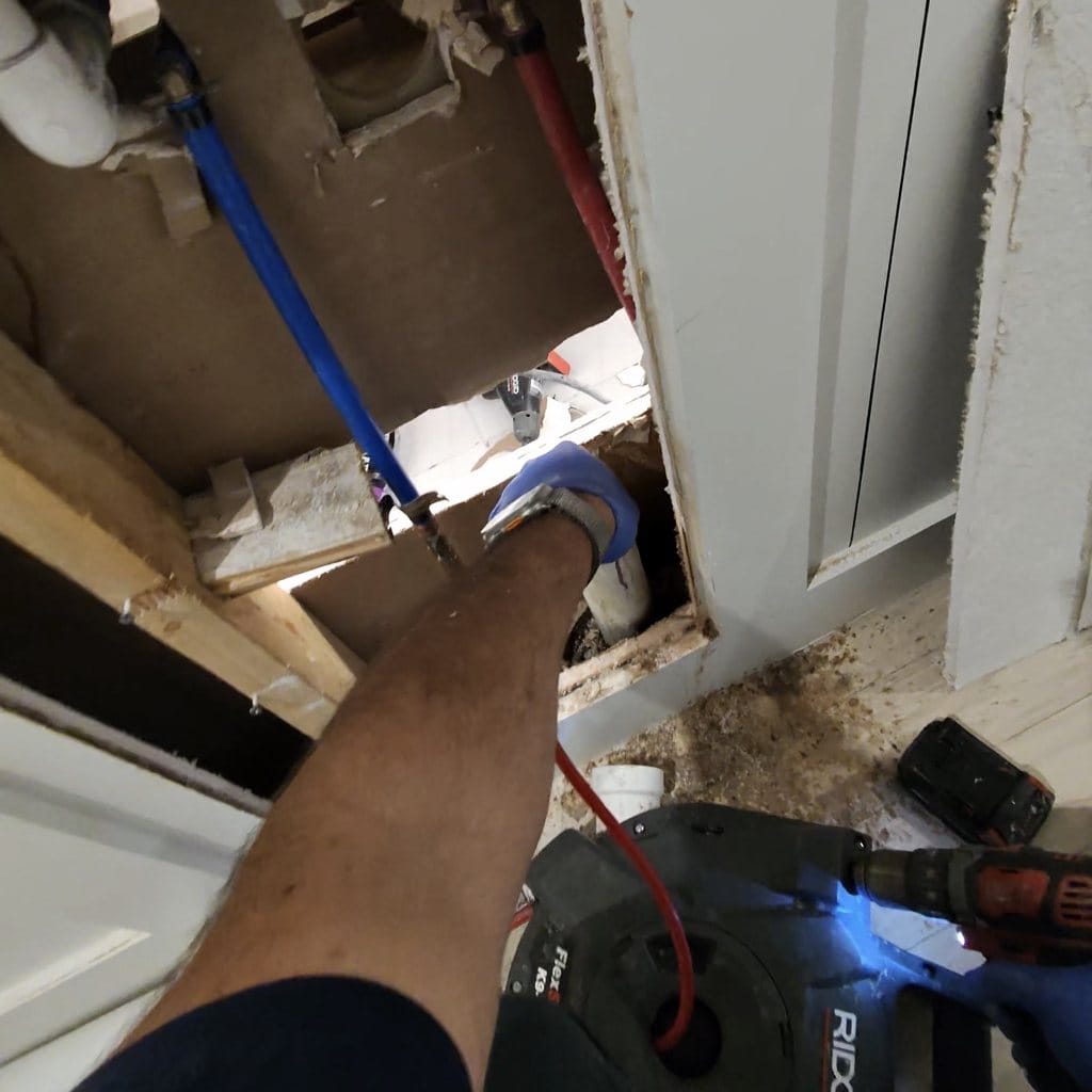 Clearing clogged drain line with RIDGID chain snake during bathroom leak repair in Frisco TX