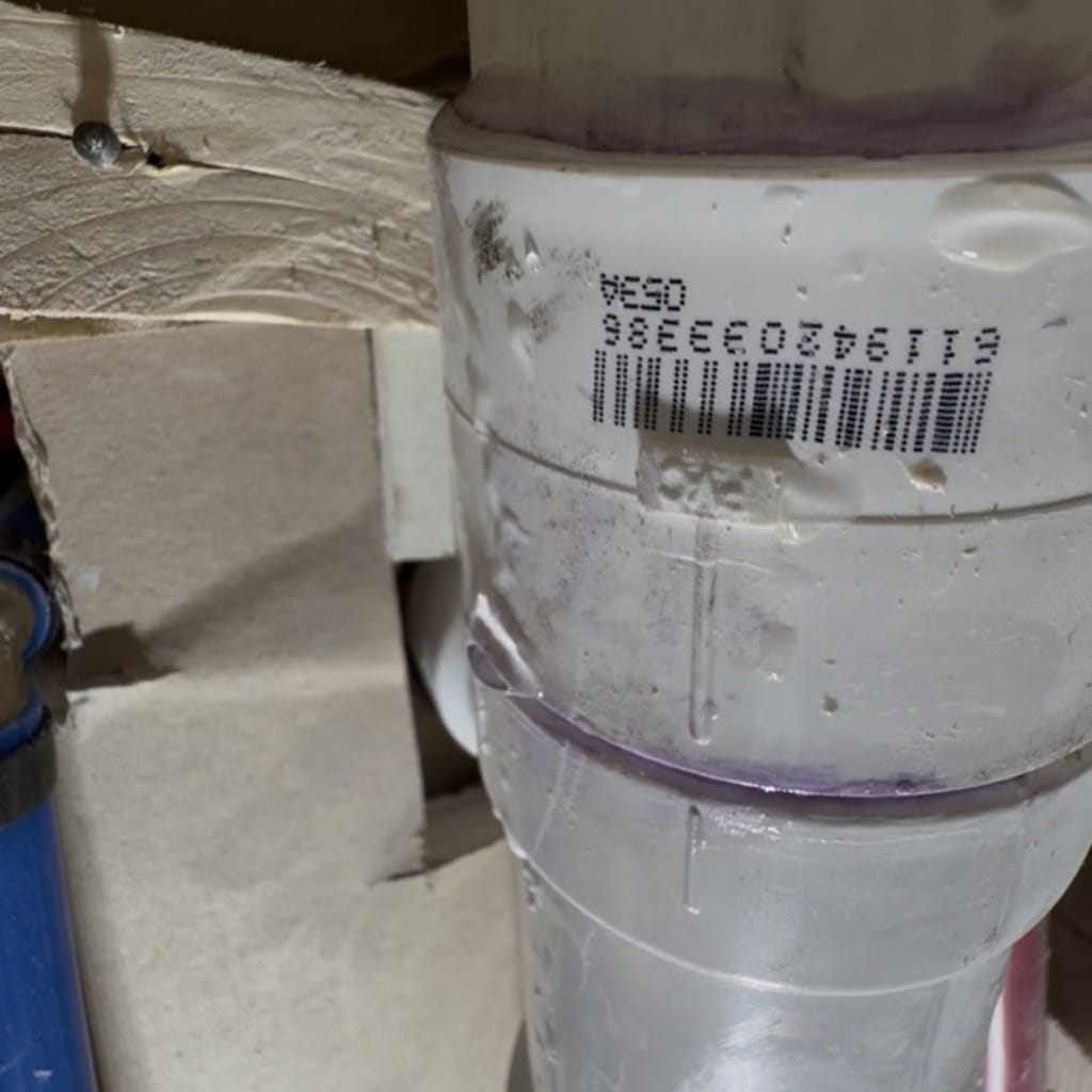 Close-up of leaking sanitary tee on PVC drain line behind wall in Frisco TX