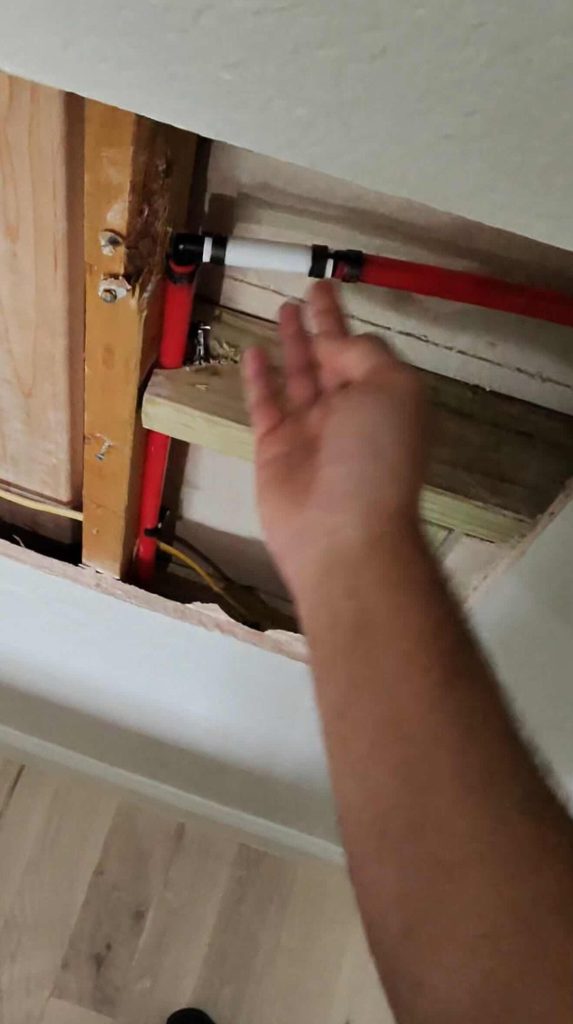 Close-up plumbing repair photo showing a half-inch PEX pipe not fully seated on a 90-degree fitting causing water leak in Frisco TX